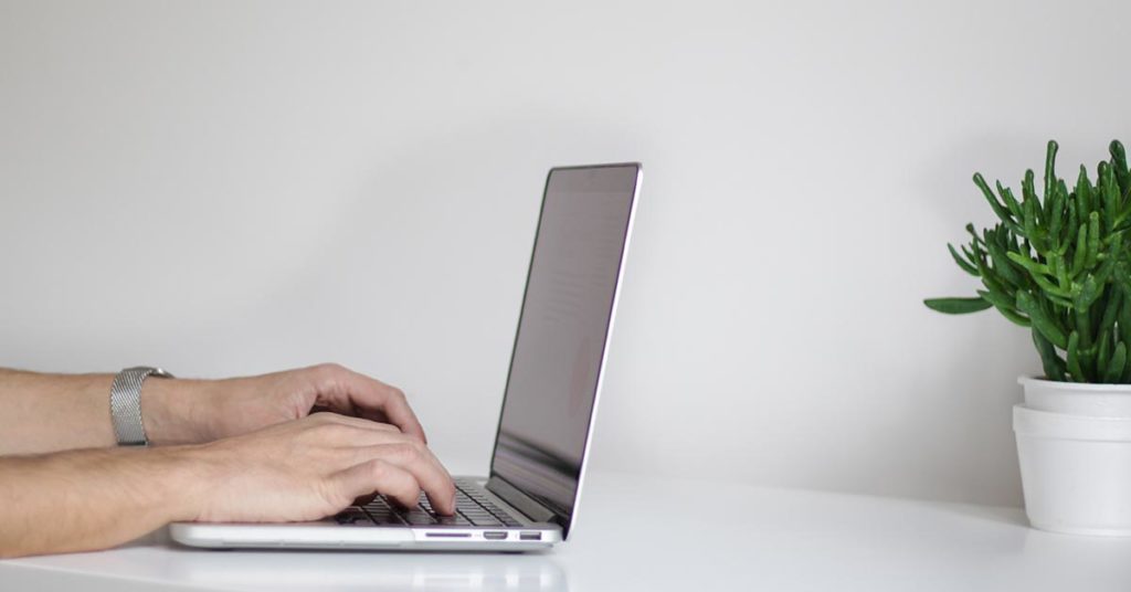 laptop on desk with hands